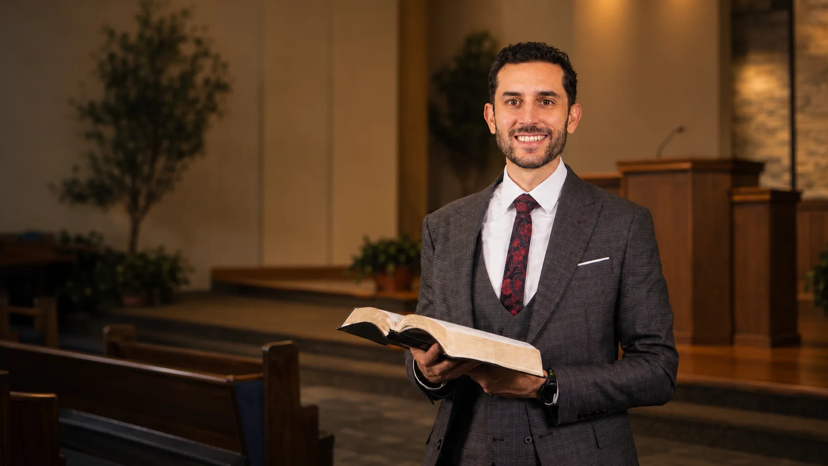 Pastor Myckal Morehouse holding an open Bible in the sanctuary at Sandpoint Seventh-day Adventist Church